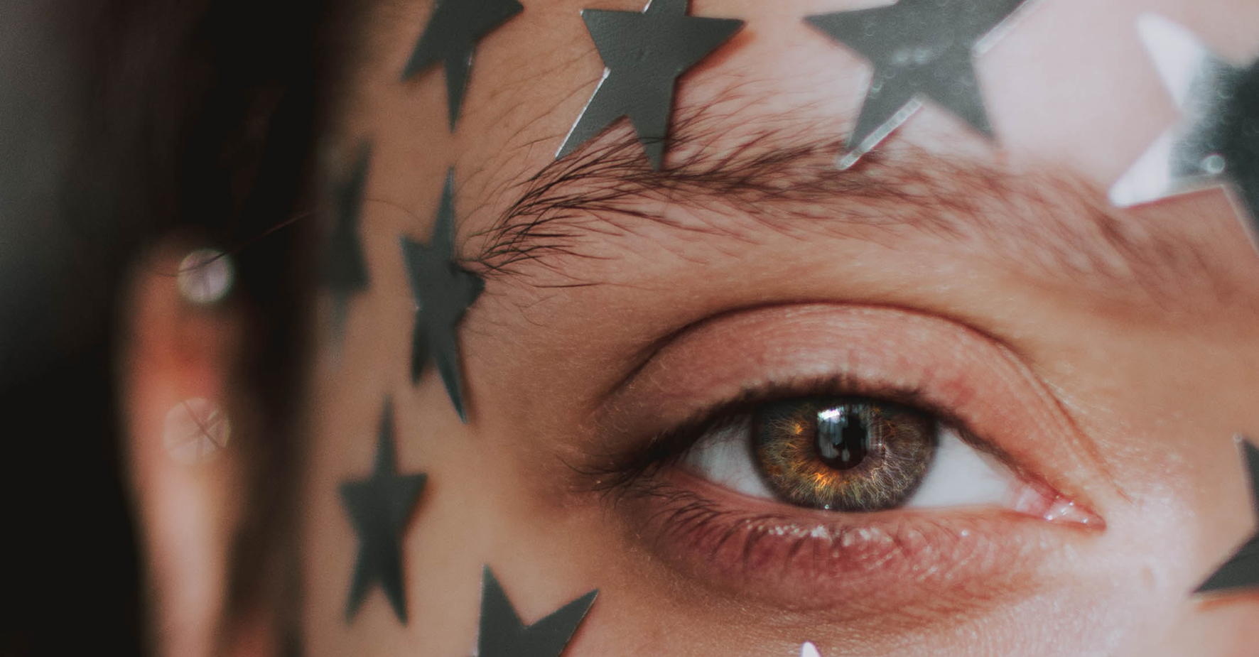 Close-up View Of Woman’s Eye With Silver Stars On Her Face Around Her Eye